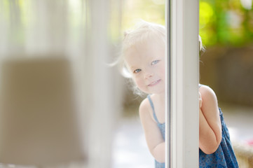 Cute little toddler girl peeking into a window