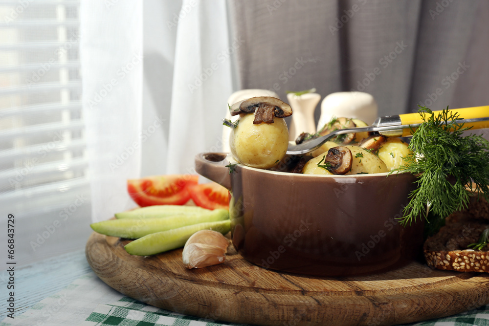 Young boiled potatoes in pan with vegetables on table in