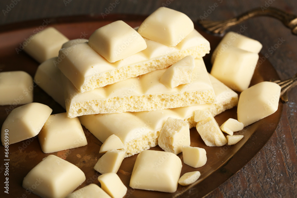White broken chocolate bar on tray, on color wooden background