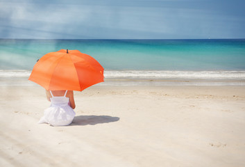 Wall Mural - Girl with an orange umbrella on the sandy beach