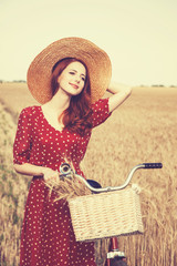 Sticker - Redhead peasant girl with bicycle on wheat field.