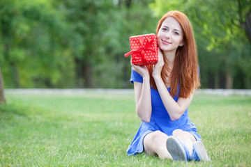 Poster - Redhead women with gift at green grass.