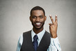 © pathdoc - Businessman giving victory two fingers sign grey wall background