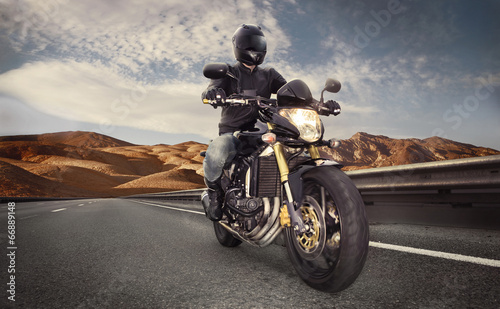 Naklejka ścienna Man seat on the motorcycle on the desert road