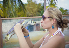 Beautiful Woman Kissing A Young Sea Turtle While On Vacation