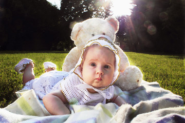 Adorable baby girl lying on green summer lawn