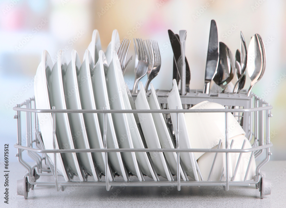 Clean dishes drying on metal dish rack on light background