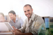 © goodluz - Smiling man in office using digital tablet