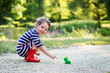 Beautiful little girl in red rain boots playing with rubber frog
