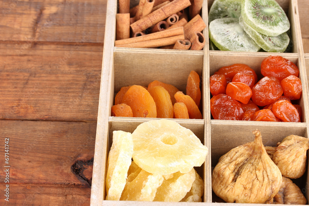 Dried fruits and cinnamon in box on wooden background