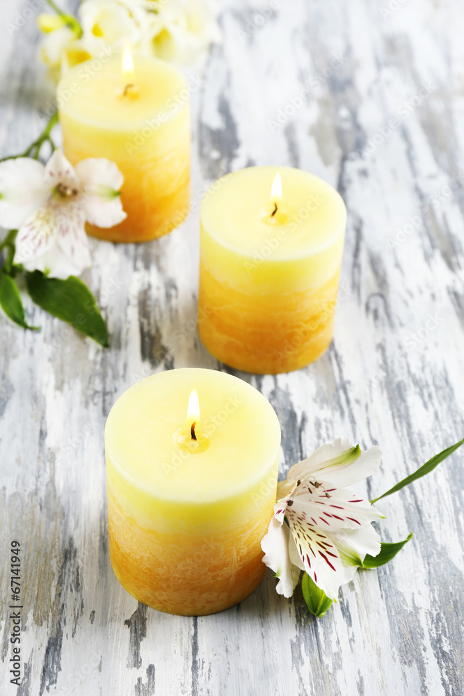Beautiful candles with flowers on wooden background