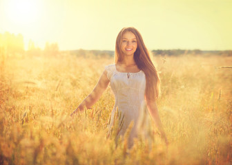 Beautiful teenage model girl in white dress running on the field