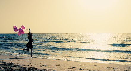 beautiful woman with colorful balloons on seaside