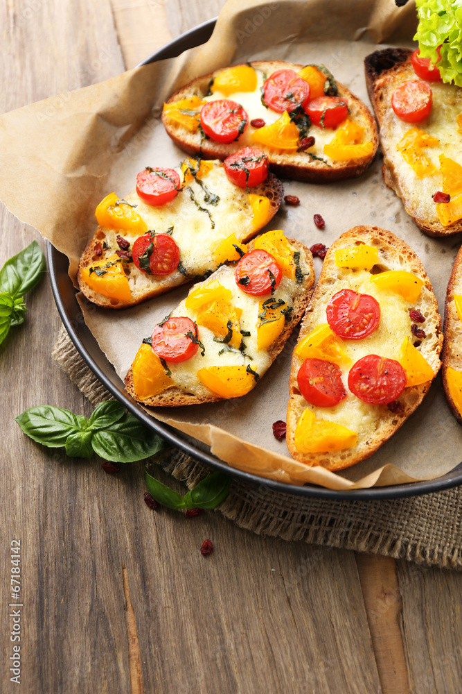 Tasty bruschetta with tomatoes on pan, on old wooden table