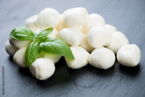 Fotografía Mini mozzarella balls with green basil leaves, horizontal shot