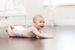 Happy seven month old baby girl crawling on a hardwood floor