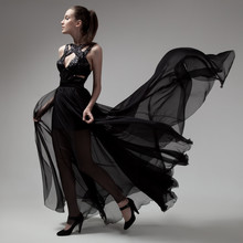 Fashion Woman In Fluttering Black Dress. Gray Background.