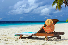 Straw Hat And Bag On A Lounge Chair At Tropical Beach