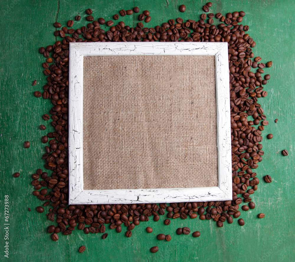Wooden frame and coffee grains on wooden background