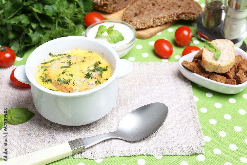 Tasty soup in saucepan on tablecloth, close up