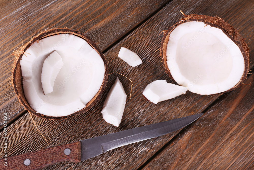 Broken coconut with knife on wooden background