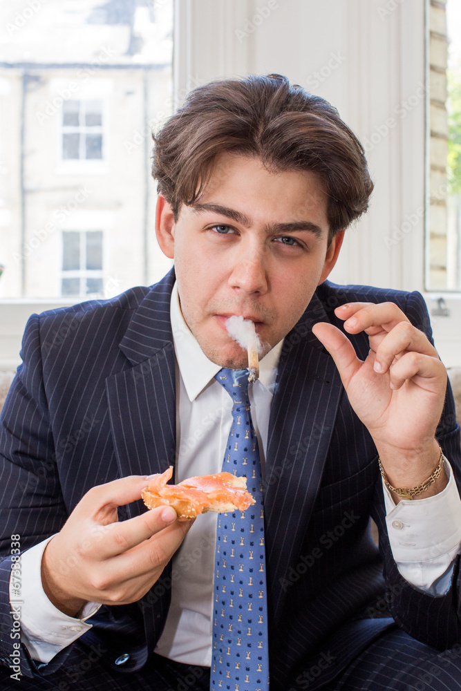 guy eats cigarette Young man smoking while eating a snack Stock Photo