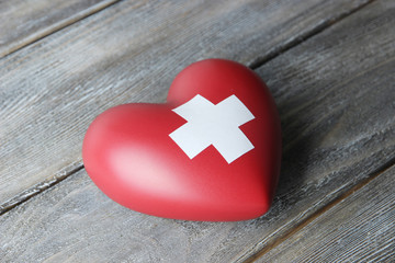 Red heart with cross sign on wooden background