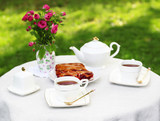 Fototapeta Morze - Coffee table with teacups and tasty pie in garden
