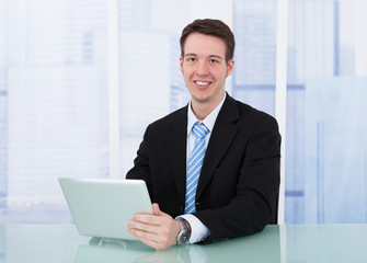 Poster - Confident Businessman Using Digital Tablet At Desk