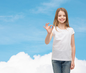 Wall Mural - little girl in white t-shirt showing ok gesture