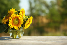 Beautiful Sunflowers On Table On Bright Background