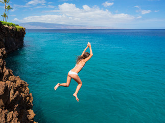 Wall Mural - Woman jumping off cliff into the ocean