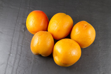 Five sun sweet apricots, one halved with stone. Prunus.