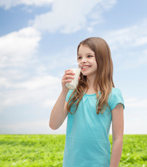 Wall Mural - smiling little girl drinking milk out of glass