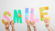 © Africa Studio - Hands holding up letters building word smile on grey background