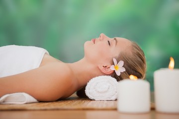 Wall Mural - Peaceful blonde lying on bamboo mat with candles