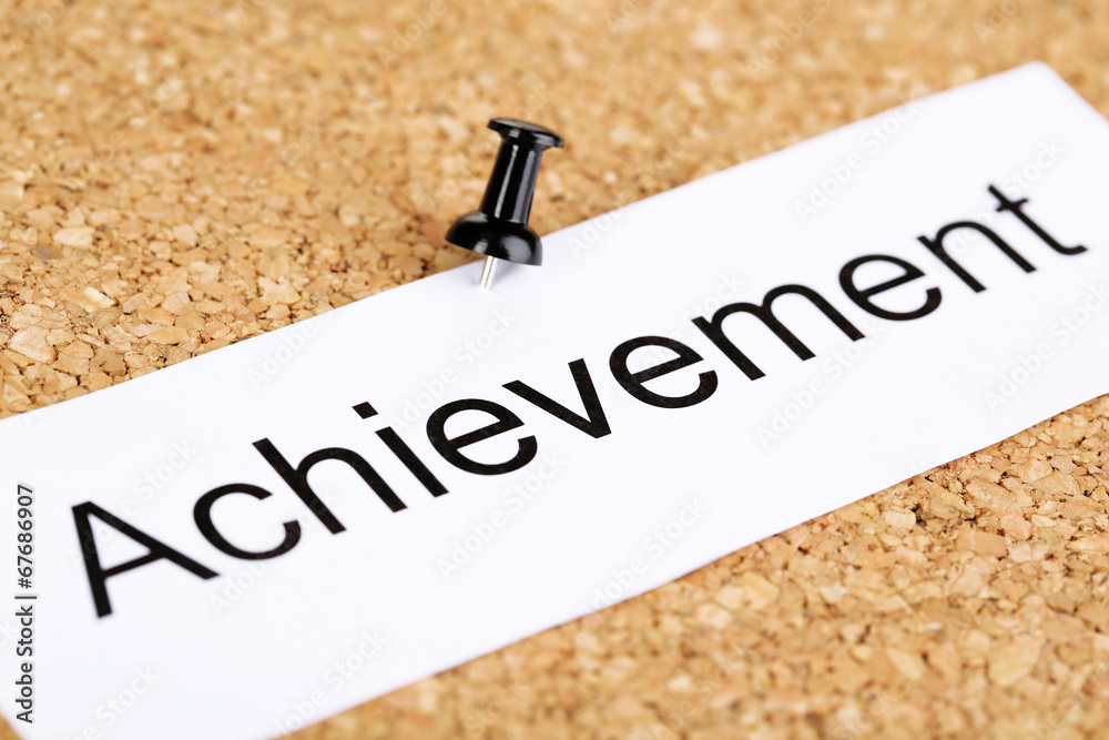 Push pin on paper with word achievement on cork board