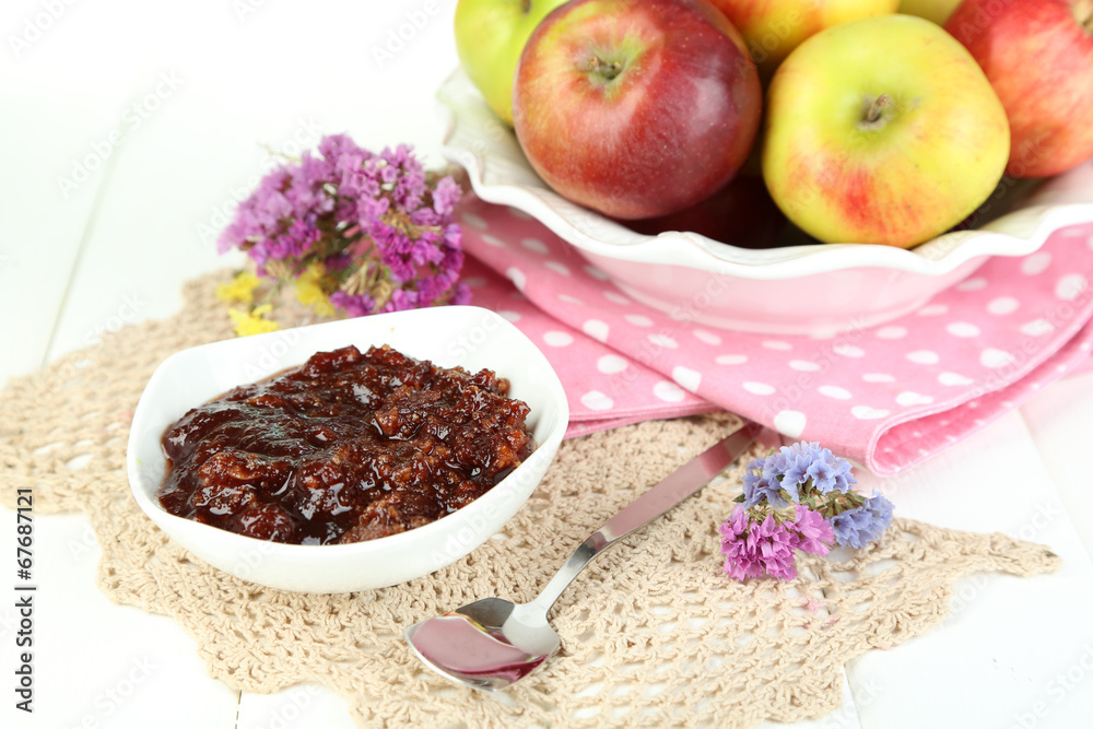 Juicy apples on plate on white wooden table