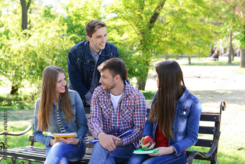 Happy students sitting in park