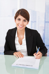 Wall Mural - Smiling Businesswoman Signing Contract At Desk