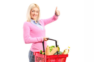 Poster - Girl holding a shopping basket full of groceries and giving a th