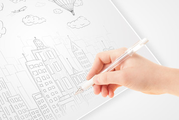 Fototapete - A person drawing sketch of a city with balloons and clouds on a