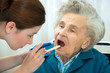 Doctor examines elderly woman for sore throat