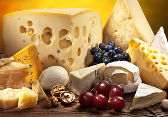 Wall Mural - Different types of cheese over old wooden table.