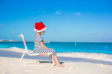 Wall Mural - Little adorable girl wearing Santa hat at tropical beach