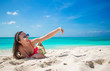 © travnikovstudio - Beautiful young woman taking a photo herself on tropical beach