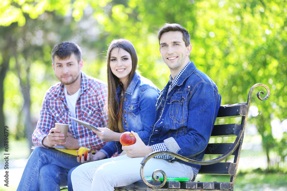 Happy students sitting in park