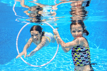 Happy active kids play underwater in swimming pool