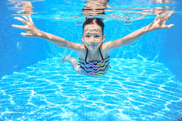 Active underwater child swims in pool, girl swimming