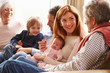 © Monkey Business - Multi Generation Family Sitting On Sofa With Newborn Baby